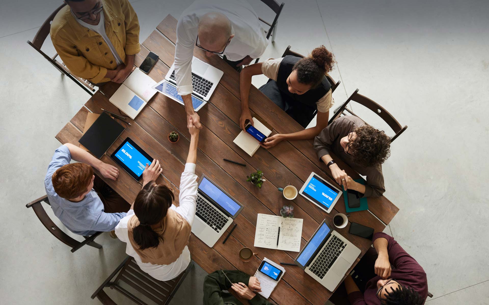 FELS Group Stellenausschreibung FELS Group Stellenausschreibung - mehrere Personen während eines Meetings, eine Begrüßung einer Kollegin durch den CEO